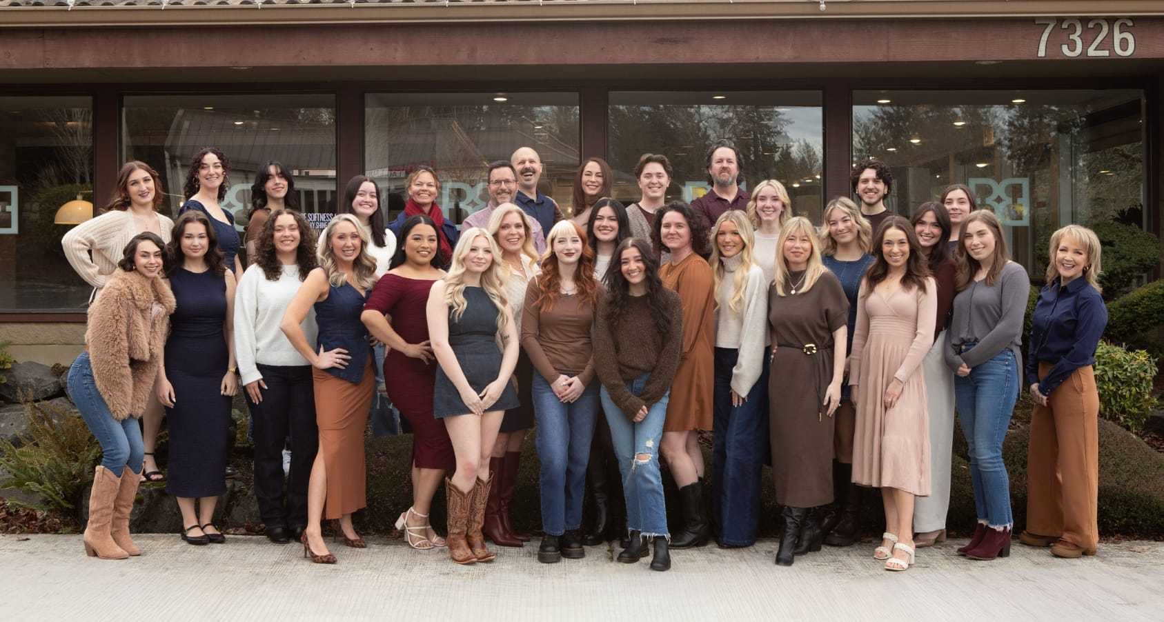 Group photo of smiling salon staff outside a building.