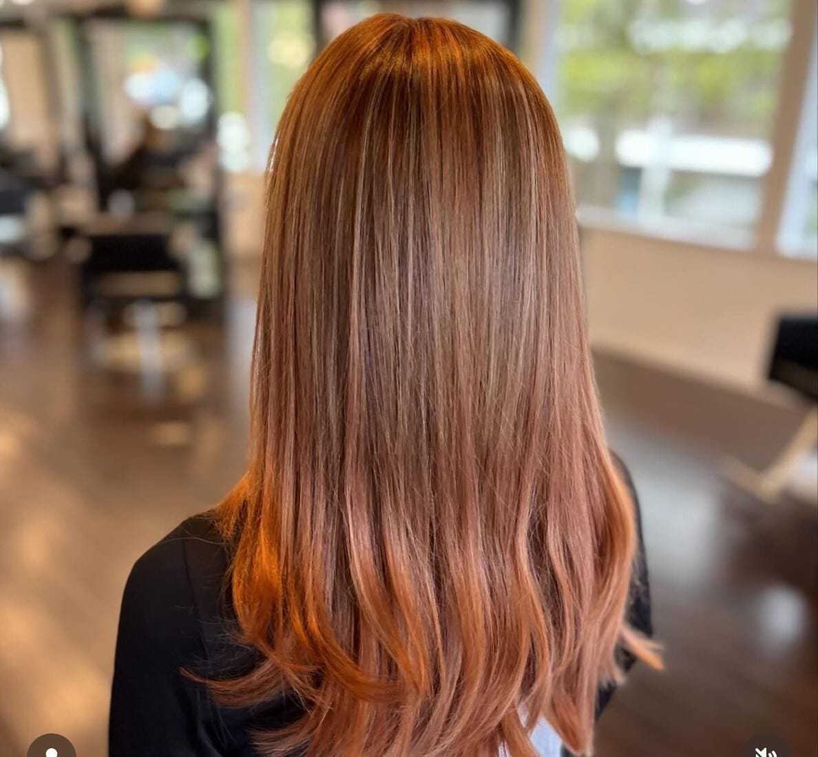 Woman with long, straight, auburn hair in a modern salon setting.