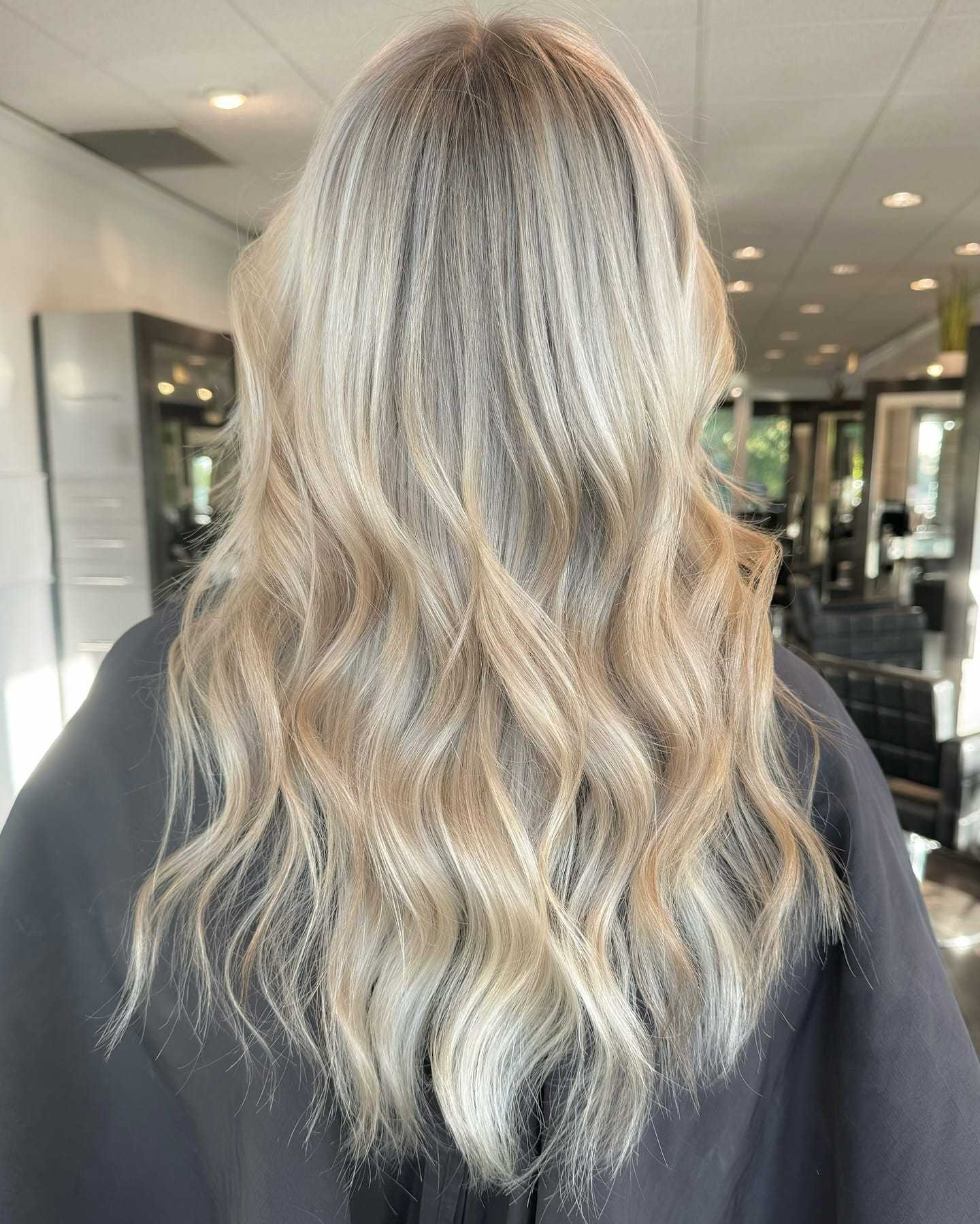 Blonde hair with soft waves and highlights styled in a salon setting.